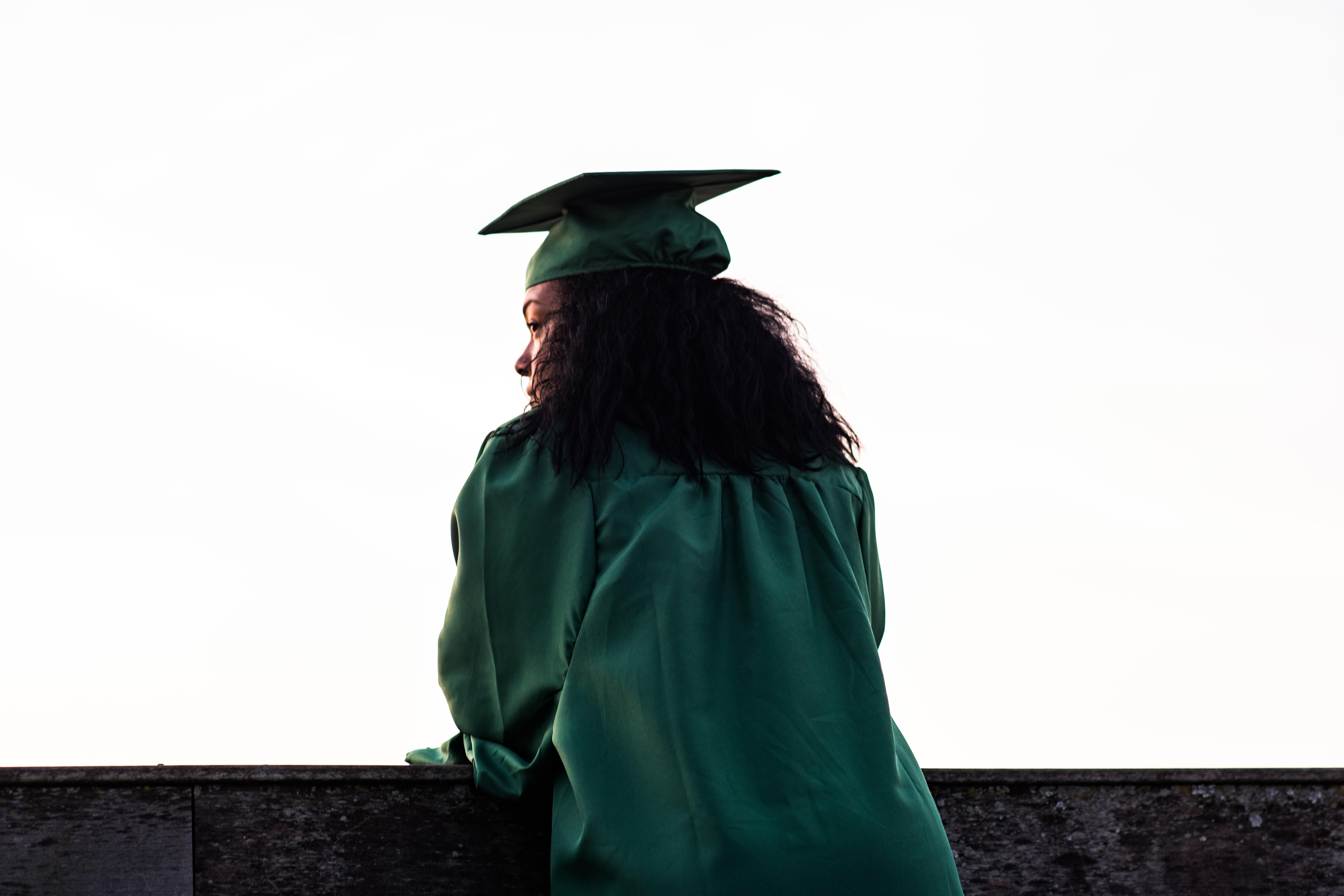 silhouette of person with long hair in graduation cap and gown